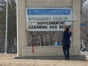 A woman changes the lettering on a sign to say that supplemental learning has begun (during the COVID-19 pandemic) at Miller Comprehensive High School in Regina, Saskatchewan on April 7, 2020.