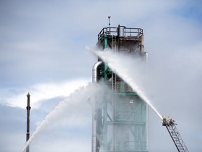 Crews spray water on a structure at the Co-op Refinery Complex after a fire broke out in Regina on Monday, August 10, 2020.
