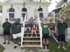 Judy Livingstone sits on the step of her new deck with four of her grandchildren. They are joined by seven of the young men who helped out with extensive renovations to her home.  Standing on the deck are, left to right, Emmett Steadman, Tucker King and Dominique Dheilly. Below them, standing left to right, are Isaac Birdsell-Tyndale, Christian Katende, Carson Sombach and Aidan Koh-Steadman. Livingstone is flanked by grandchildren Evelina Tocker (seated, left) and Emmett Tocker. Seated in front of Judy are grandchildren Wyatt Tocker, left, and Owen Tocker.