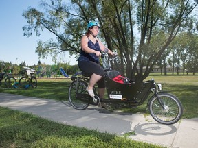 Annabel Townsend, Owner of the Penny University which is currently operating as an online book seller, rides her delivery bike along the path in Les Sherman Park in Regina, Saskatchewan on August 19, 2020.