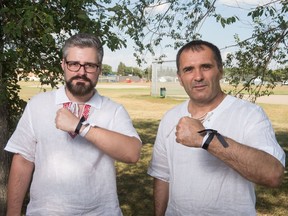 Vitaly Jaroshevsky, left, and Vitaly Shevrov hold up black and white ribbons in a park off of Lyons Street in Regina on Aug. 21, 2020. The men, both from Belarus, will be part of an upcoming event to show solidarity with citizens in Belarus they feel have been wrongfully treated by the government.