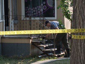 Seorang pekerja forensik menggunakan kapas di tangga depan di lokasi investigasi kematian di blok 1200 Cameron Street di Regina, Saskatchewan pada 25 Agustus 2020. Joshua Larose dituduh membunuh Matthew Bossenberry di sana atau sekitar 24 Agustus tahun itu.