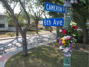 Memorial flowers hang on a light post on the corner of 6th Avenue and Cameron Street in Regina, Saskatchewan on August 26, 2020. Behind, the front yard of a home is taped off while police continue a death investigation.
