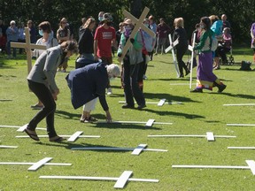 People whose lives have been affected by addictions pick up crosses meant to symbolize those who have died from drug overdose during an event held in the park across from the Saskatchewan Legislative Building to mark International Overdose Awareness Day in Regina, Saskatchewan on August 31, 2020.