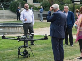 Dan McCann, founder of Precision AI, left, explains the company's drones, which were built to selectively apply herbicide in agriculture, following a news conference on Research Drive in Regina, Saskatchewan on August 20, 2020. The news conference was regarding the use of AI technology in herbicide application.