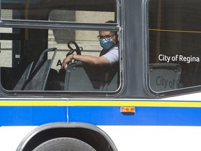 A man wearing a mask looks out the window of a city transit bus in downtown Regina, Saskatchewan on August 24, 2020.