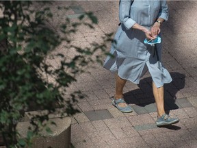 A woman carries a mask in downtown Regina on July 28, 2020.