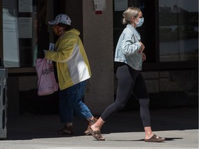Two pedestrians wear masks in downtown Regina, Saskatchewan on July 28, 2020.