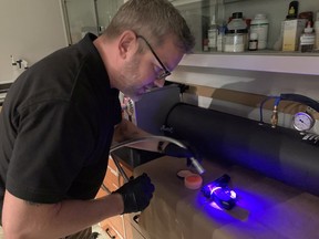 Cpl. Keith Malcolm, one of the officers in charge of the Regina Police Service's Forensic Identification Section, demonstrates use of a forensic light source in locating fingerprints on a firearm. HEATHER POLISCHUK/Regina Leader-Post