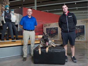 Dan Toppings, executive director of the RCMP Heritage Centre, left, and Justin Williams, education and programming team member for the centre, stand with Indi, a former trainee RCMP dog, inside the centre on Dewdney Avenue in Regina, Saskatchewan on Sept. 24, 2020.