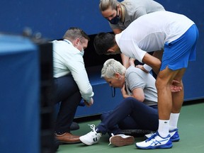 Novak Djokovic of Serbia and a tournament official tend to a linesperson who was struck with a ball by Djokovic against Pablo Carreno Busta of Spain.