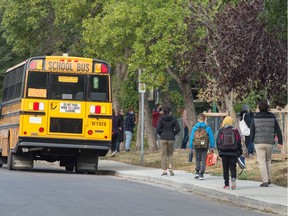 As students return to classes, people walk along the sidewalk to Connaught Community School in Regina, Saskatchewan on Sept. 8, 2020.