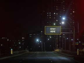 "Stay Home" is displayed on a sign over an empty road in Toronto, on March 25.
