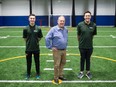 Aubrey Steadman stands between his two sons — Emmett, left, and Aidan, right — on the football training turf at the new Regina Sports Performance Centre.