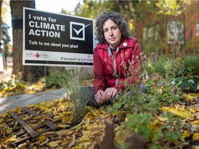 Amy Snider sits next to a climate-themed lawn sign at her home in Regina on Oct. 8, 2020.