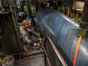 Mike Davis, a mill operator, monitors robotic welders laying beads into a section of pipe in one of the mills at the Evraz steel plant in Regina in April. Workers at the plant working in the tubular division, which manufactures pipe for large scale industrial projects, are facing the prospect of severe layoffs.