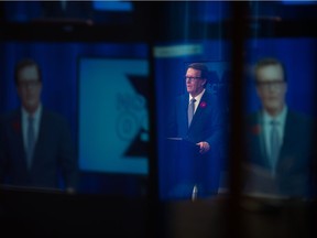 Regina mayoral candidate Michael Fougere is seen through glass speaking during the Regina mayoral debate. Fougere is seeking a third term as mayor of Regina.