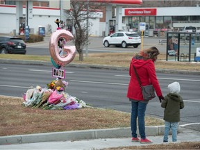 A woman and a child look at a memorial on Albert Street in Regina, Saskatchewan on Nov. 5, 2020. On Nov. 4, a woman was killed crossing the street near the location of the memorial.