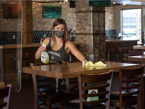 A worker sanitizes  table inside the Cathedral Social Hall in Regina, Saskatchewan on Nov. 13, 2020.