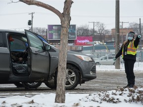 An SGI employee signals to a motorist in front of the SGI drivers examinations office in Regina, Saskatchewan on Nov. 17, 2020.