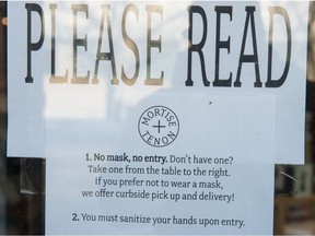 A sign indicating customers must wear masks hangs on the door of Mortise And Tenon in Regina, Saskatchewan on Nov 18, 2020.