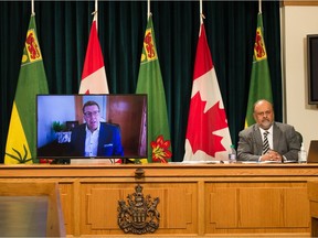 Premier Scott Moe, centre, speaks to media remotely from his home while being displayed on a television set in a news conference regarding COVID-19 at the Saskatchewan Legislative Building in Regina, Saskatchewan.