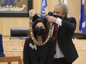 Jim Nicol, chief returning officer for Regina's 2020 municipal elections, right, places The Mayor's Chain of Office around the neck of Mayor Sandra Masters during a swearing in ceremony of the 2020 - 2024 city council at City Hall.