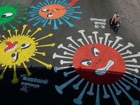 A motorcyclist rides past a mural of the COVID-19 coronavirus in Chennai, India, on April 13, 2020.