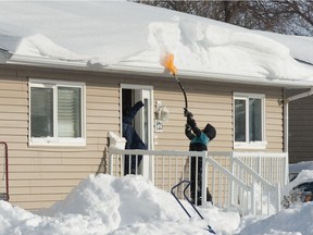 A person pokes at a drift on the roof after a massive dump of snow in Swift Current, Saskatchewan on Nov. 9, 2020.