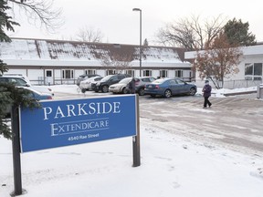 A masked person walks through the parking lot of Parkside Extendicare.