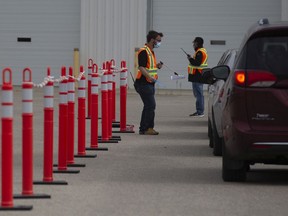 Health care workers wait outside for patients at a drive-thru testing site for Covid-19 in Saskatoon, Saturday, September, 12, 2020.