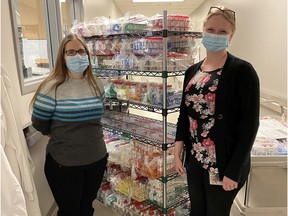 REGINA, SASK. : December 11, 2020 -- Amanda Lang (left), clinical microbiologist at the Roy Romanow Provincial Laboratory (RRPL), and Jessica Minion (right), provincial clinical lead for Public Health in Laboratory Medicine, stand with a shelf filled with reagents used for PCR testing of COVID-19 samples in the Roy Romanow Provincial Laboratory. (Photo courtesy of Saskatchewan Health Authority)