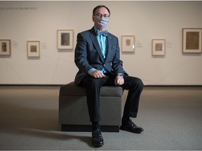 Timothy Long, head curator at the MacKenzie Art Gallery, sits in front of some of the art on display at the gallery in Regina, Saskatchewan on Dec. 11, 2020.