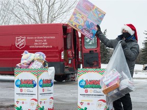 Greg Morgan of the Regina radio station CJME loads toys into a bag during the Santa's Anonymous drive-thru toy donation event held at the Canadian Tire on the east end of Regina, Saskatchewan on Dec, 12, 2020. The toys collected are to be delivered by Salvation Army to families in need this Christmas.