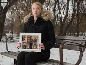 Aleesa Blight sits holding a photo of her family in Wascana Park in Regina on Dec. 12, 2020. Blight lost her spouse Christopher Salateski to an overdose on Nov. 23. Blight and Salateski often visited Wascana Park, near the Legislative Building.