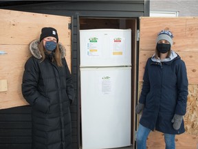 Sarah Mitten, left, and Danielle Froh stand together at the new community fridge behind the Regina Family Pharmacy on Dewdney Avenue on Dec. 17, 2020.