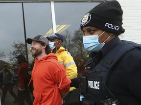 Adamson BBQ owner Adam Skelly is led away from his restaurant by Toronto Police on November 26, 2020.