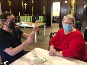 Saskatchewan NDP Leader Ryan Meili, left, prepares a vaccine for Gloria Welyki as he works on the province's vaccine effort at a seniors' home on Saturday. (Photo submitted by Ryan Meili)