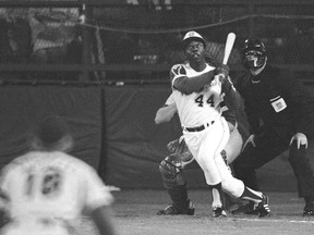 Atlanta Braves' Hank Aaron eyes the flight of the ball after hitting his record-setting 715th career homer in a Major League Baseball game against the Los Angeles Dodgers on April 8, 1974. Dodgers pitcher Al Downing and umpire David Davidson look on. Aaron died Friday at 86.