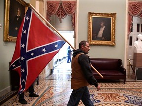 A supporter of President Donald Trump carries a Confederate battle on the second floor of the U.S. Capitol near the entrance to the Senate after breaching security defences, in Washington, U.S., January 6, 2021.
