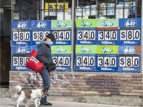 A pedestrian wearing a mask and walking her dog walks past Lotto Max and Lotto 649 advertising on Toronto's Broadview Avenue during the Covid 19 pandemic, Tuesday October 20, 2020.