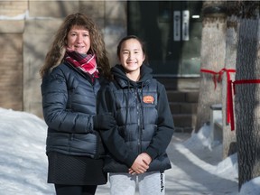 Cristina Ruiu, left, and her daughter Victoria Bateman stand in front of Holy Rosary School in Regina, Saskatchewan on Feb. 2, 2021. Ruiu is the chair of the Holy Rosary School Parent Council, which is petitioning the school division to keep the school open.