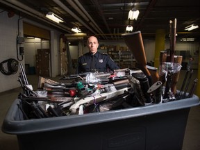 Supt. Corey Zaharuk of the Regina Police Service stands behind a bin full of seized firearms destined for destruction, which were being kept in a secure area in the basement of police headquarters on Feb. 3, 2021.