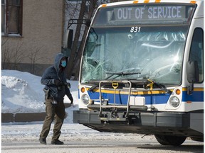 A Regina Police Service photographer looks at a Regina city transit bus, which struck a man on Broad Street in Regina, Saskatchewan on Feb. 3, 2021. The pedestrian was declared dead at the hospital.