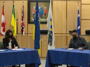 Regina Mayor Sandra Masters, seated left, and Carry the Kettle Nakoda Nation (CTK) Chief Brady O'Watch sign a memorandum of understanding between CTK and the City of Regina at Regina City Hall in Regina, Saskatchewan on Feb. 11, 2021.