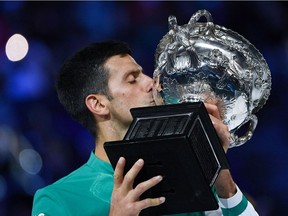 Serbia's Novak Djokovic kisses the Norman Brookes Challenge Cup trophy following his victory against Russia's Daniil Medvedev in their men's singles final match on day fourteen of the Australian Open tennis tournament in Melbourne on February 21, 2021.