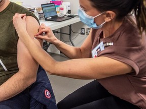 Registered nurse Lianne Korte sterilizes the arm of intensive care specialist Dr. Hassan Masri before administering the Pfizer COVID-19 vaccine on Dec. 22, 2020.