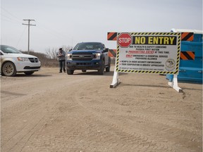 An individual working security detail at a checkpoint on the edge of Pasqua First Nation speaks to a driver through the window of a vehicle leaving the area in April 2020. The First Nation is restricting traffic in and out of its community due to the COVID-19 pandemic. BRANDON HARDER files