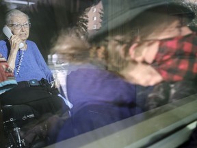 Joan Moore, left, speaks on the phone to her daughter Pam Moore, right, through her room's window at Extendicare Parkside. Joan Moore contracted COVID-19 in early December, and has since recovered.