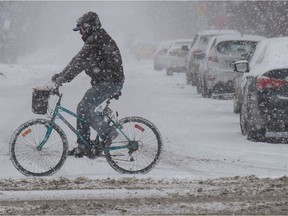 A man rides his bike through a flurry on 13th Avenue in Regina, Saskatchewan on Mar. 9, 2021.